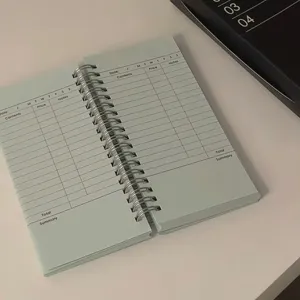 A6 slim spiral planner notebook with detailed daily schedule and expense tracking pages.