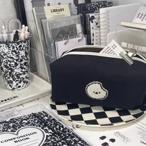 Black canvas pencil pouch detail showing cute puppy embroidery and clean white zipper setup on desk.