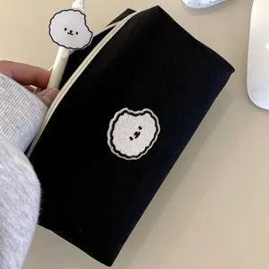 Detailed view of a black canvas pencil case featuring cute puppy embroidery and smooth zipper.