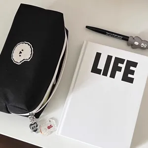 Black canvas pencil case detail featuring a cute dog patch and a stylish zipper charm.