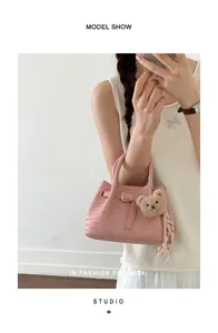 Chic pink woven handbag for women, elegant top handle design with cute bear pendant and strap.