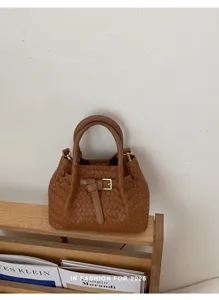 Chic brown woven leather handbag for women, stylish top handle bucket bag with belt detail.