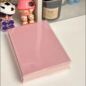 Détail de carnet rose avec couverture de protection transparente et design minimaliste.