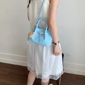 Women summer blue woven bucket handbag cross-body bag with cute bear pendant on model view.
