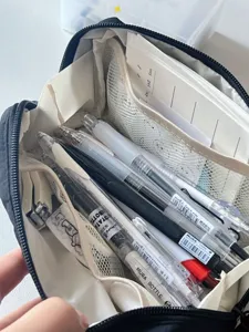 Detail shot of the black canvas pencil pouch showing large capacity and multi-layer mesh storage.