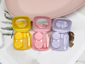 Compact portable contact lens case with mirror, bottle and tweezers in three pastel colors.