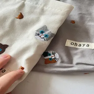Detailed close-up view of cute canvas makeup pouch featuring cat embroidery and fabric label.