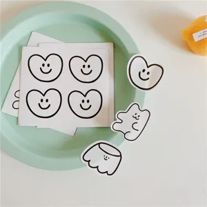 Close-up detail of cute minimalist smiley heart and pudding stickers on green tray.
