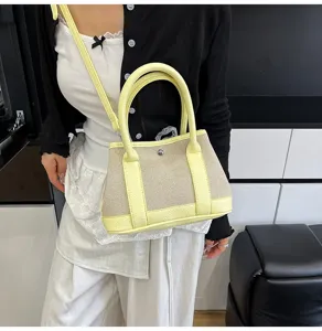 Detailed view of stylish canvas crossbody bag with contrast leather trim and top handles.
