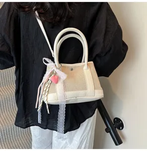 Chic small canvas leather contrast handbag with cute lace and heart charm for stylish women.