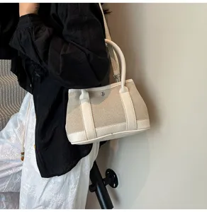 Canvas and leather tote bag detail, featuring contrast color design and sturdy top handles.