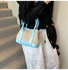 Detail shot of the two-tone canvas handbag with blue leather trim carried on stairs.