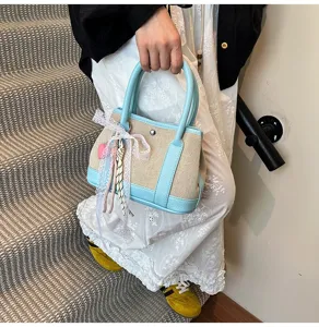 Detail shot of the contrast color canvas handbag featuring delicate lace ribbon and blue leather trim.