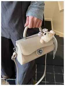 Chic borsa a tracolla beige con chiusura metallica, simpatico ciondolo orsetto e nappina.