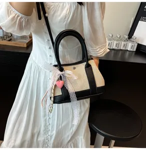 Chic color-block canvas and leather tote bag featuring elegant lace bow and heart charm detail.