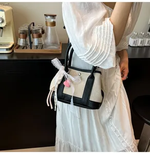Detailed view of fashionable contrast canvas handbag with lace bow and pink heart charm.