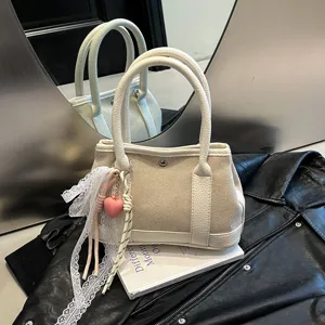 Chic beige canvas handbag with white leather trim, lace ribbon, and heart charm for women