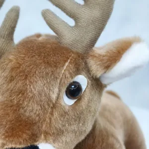 Vue rapprochée du détail de la tête de cerf en peluche, tissu doux et yeux réalistes.