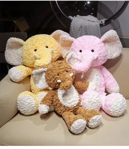 Nahaufnahme von süßen flauschigen Plüschelefanten in Gelb, Rosa und Braun auf dem Sofa.