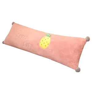 Pink plush long body pillow with cute pineapple embroidery and corner pom poms for bed decor.