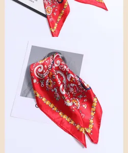 Close-up detail of the vibrant red satin silk scarf featuring classic paisley and floral patterns.