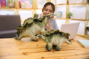 Vue détaillée de peluche dinosaure de simulation avec des animaux en peluche sur le bureau.