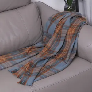 Detailed view of a soft blue and orange plaid scarf draped elegantly on a grey sofa.