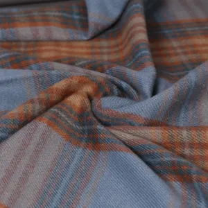 Soft plaid winter scarf detail shot, blue and orange tartan fabric texture close up.