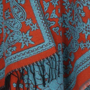 Detailed view of bohemian paisley fringe cashmere-feel shawl, orange and blue woven texture.