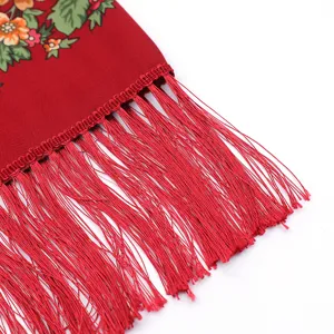 Close-up detail of red ethnic style floral scarf with delicate fringe, autumn winter shawl.
