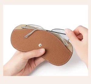Detalle del estuche para gafas de cuero marrón portátil con cierre de botón a presión.