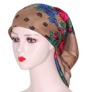 Close-up detail of the traditional floral print square headscarf showing intricate brown design.