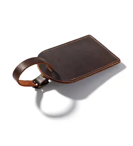 Detail shot of dark brown crazy horse leather luggage tag with fine stitching and metal buckle.