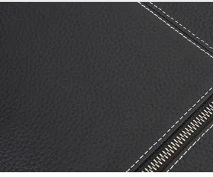 Close-up detail of black genuine leather men bag with white contrast stitching and metal zipper.