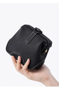 Black genuine leather cosmetic pouch detail, pebbled texture with white contrast stitching.