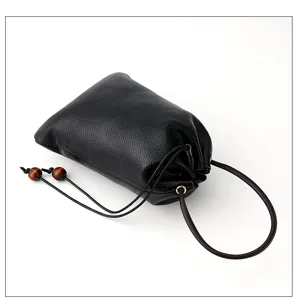 Detail view of black genuine leather lucky bag coin purse with drawstring and wood beads.