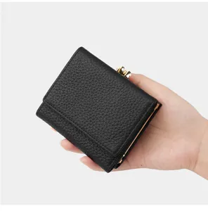 Detailed close-up view of the black leather trifold wallet featuring gold kiss-lock clasp.