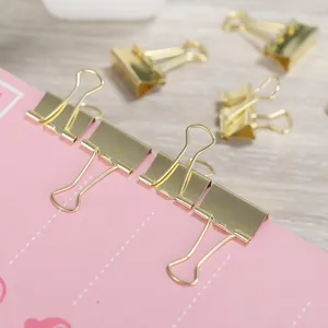 Gold binder clips detail shot, metal paper clamps for office and school stationery organization.