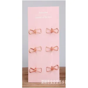 Roségoldene metallklammern büroklammern set von sechs auf einer rosa karte befestigt.