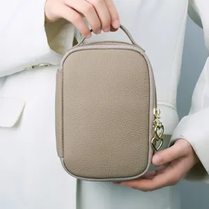 Genuine leather portable cosmetic bag with handle and heart charm for travel and storage.