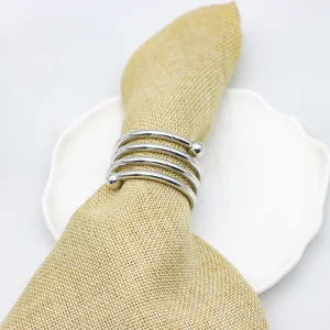 Porte-serviette en spirale en metal argente avec serviette beige pour decoration de table.