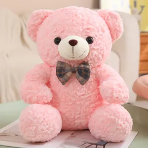 Cute pink teddy bear plush toy with plaid bow tie, sitting stuffed animal pillow for kids.