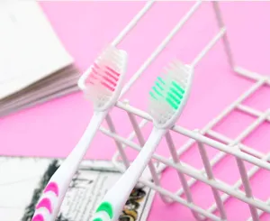 Soft bristle toothbrush detail shot showing white handle and colorful bristles in holder.