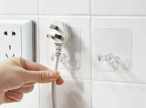 Transparent plug hook trace-free wall mount adhesive socket cord holder for home and office use.