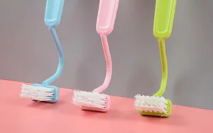 Detail view of the Japanese curved S-shaped plastic cleaning brush with soft white bristles.