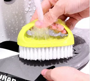Colorful egg-shaped shoe cleaning brush detail showing white bristles and green plastic handle in use.