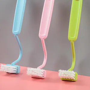Close-up view of Japanese curved S-type plastic cleaning brush with soft bristles and long handle.
