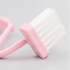 Close-up detail of the curved S-shaped toilet brush head with soft white bristles and pink handle.