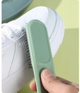 Dettaglio spazzola scarpe setole morbide manico lungo verde delicato pulizia domestica.