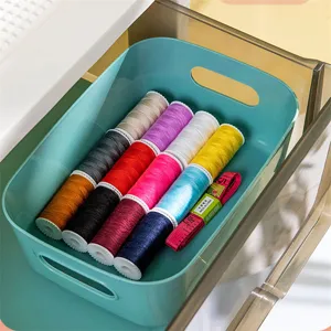 Vue détaillée d'une boîte de rangement de bureau en plastique sarcelle avec des fils à coudre.